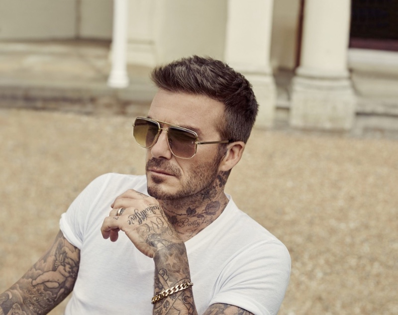 Relaxing in a white t-shirt, David Beckham wears DB Eyewear sunglasses.