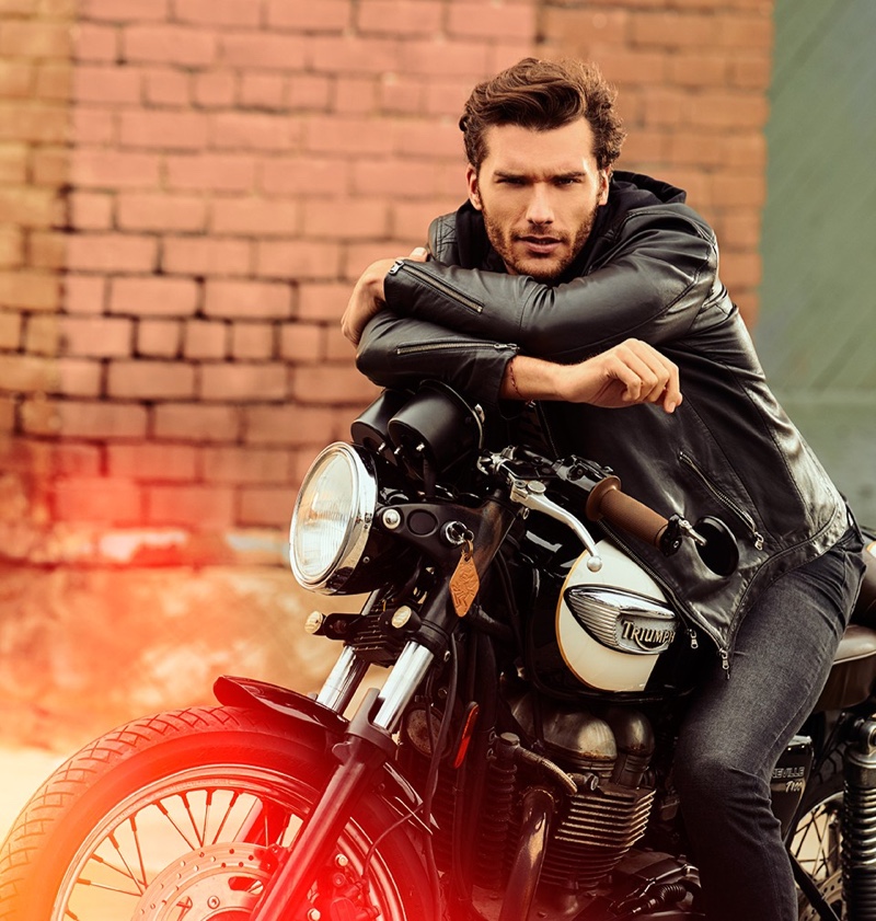 Posing on a motorcycle, Aurelien Muller sports a leather jacket and jeans from IKKS.