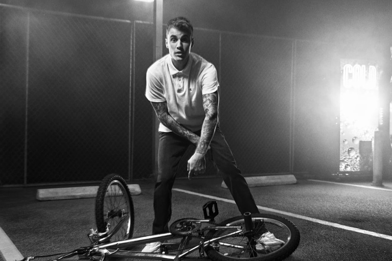 Posing with a bike, Justin Bieber sports a polo shirt and jeans for Calvin Klein's spring-summer 2020 campaign.