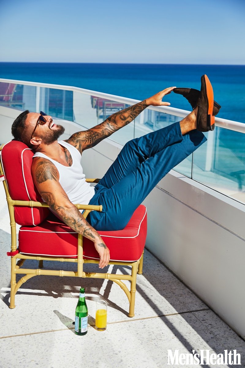 Relaxing, Maluma sports a Calvin Klein tank with Old Navy pants, Persol sunglasses, and Santoni suede loafers.