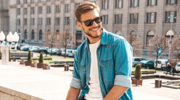 The Essential Items That Every Man Needs in His Wardrobe Smiling Male Model Denim Jacket Jeans Sunglasses