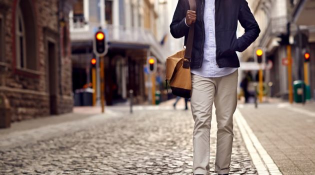 Minimalist Style Trends for Travel Black Man Cobblestone Streets Bag Jacket Khaki Pants