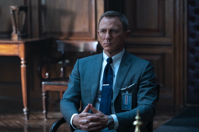 Portraying James Bond in No Time to Die, Daniel Craig wears a Tom Ford dark blue wool-silk check O'Connor notch lapel jacket and tailored trousers. He accessorizes with a Tom Ford sky blue poplin collared shirt and dark blue diagonal silk tie. | Photo courtesy of Tom Ford | Photo Credit: Nicola Dove © 2020 Danjaq, LLC, and MGM. All Rights Reserved.