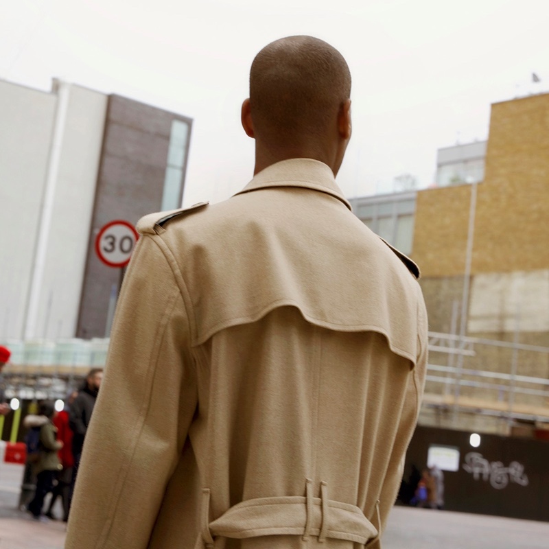 Connecting with Dolce & Gabbana, Sacha M'Baye dons a classic trench coat.