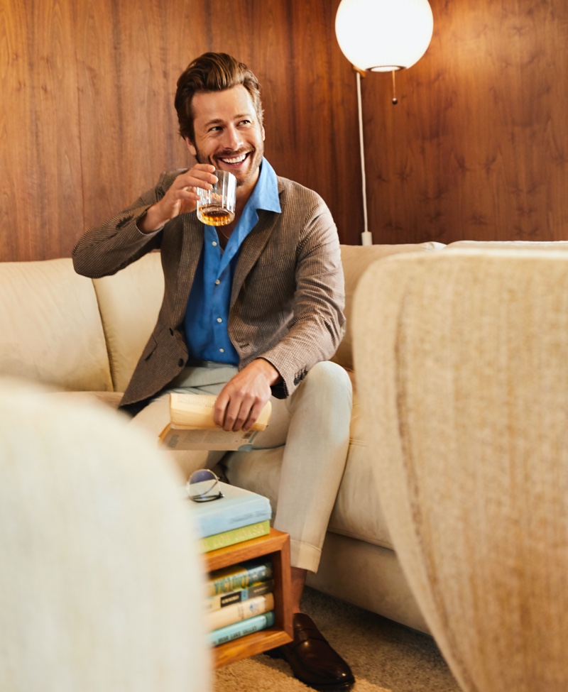 Enjoying a drink, Glen Powell wears an Edios seersucker blazer and linen shirt. Powell completes his look with Reiss pants and To Boot New York loafers for Bloomingdale's spring 2020 Mix Masters campaign. 