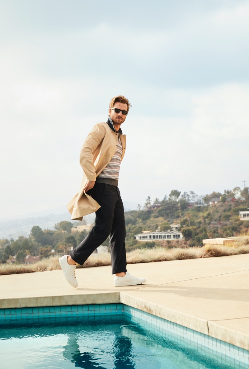 Making a case for classic style, Glen Powell sports a Rag & Bone trench coat, Z Zegna striped polo, Collegium white sneakers, and Ray-Ban sunglasses for Bloomingdale's spring 2020 Mix Masters campaign. 