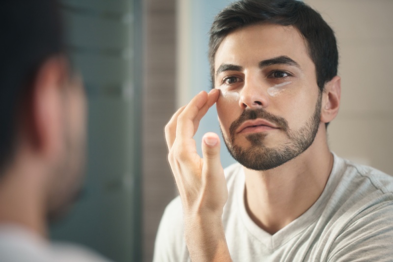 Hispanic Man Applying Face Cream Mirror Grooming