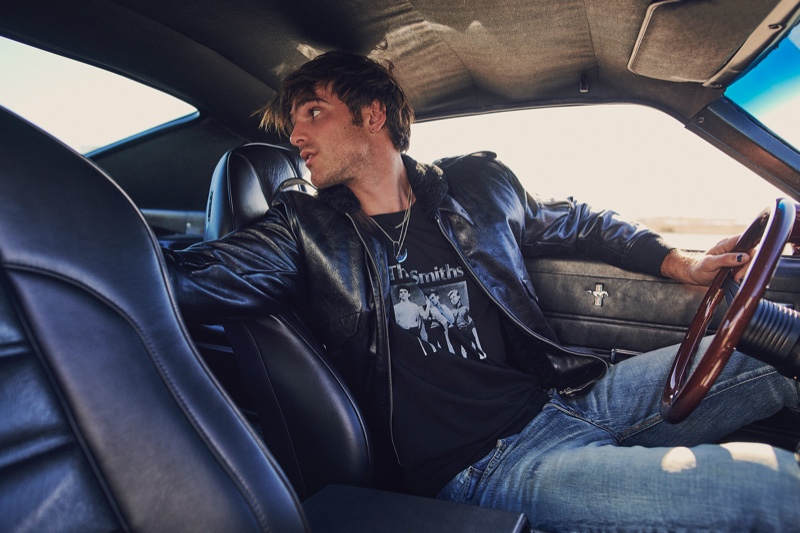 A cool vision, Jacob Elordi gets behind the wheels of a vintage car. The Euphoria star wears a Saint Laurent t-shirt, leather racer jacket, and jeans for VMAN.