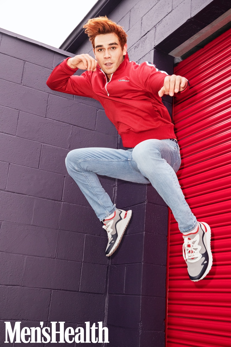 KJ Apa rocks a red track jacket by Ben Sherman with Banana Republic jeans and Michael Kors sneakers for Men's Health.