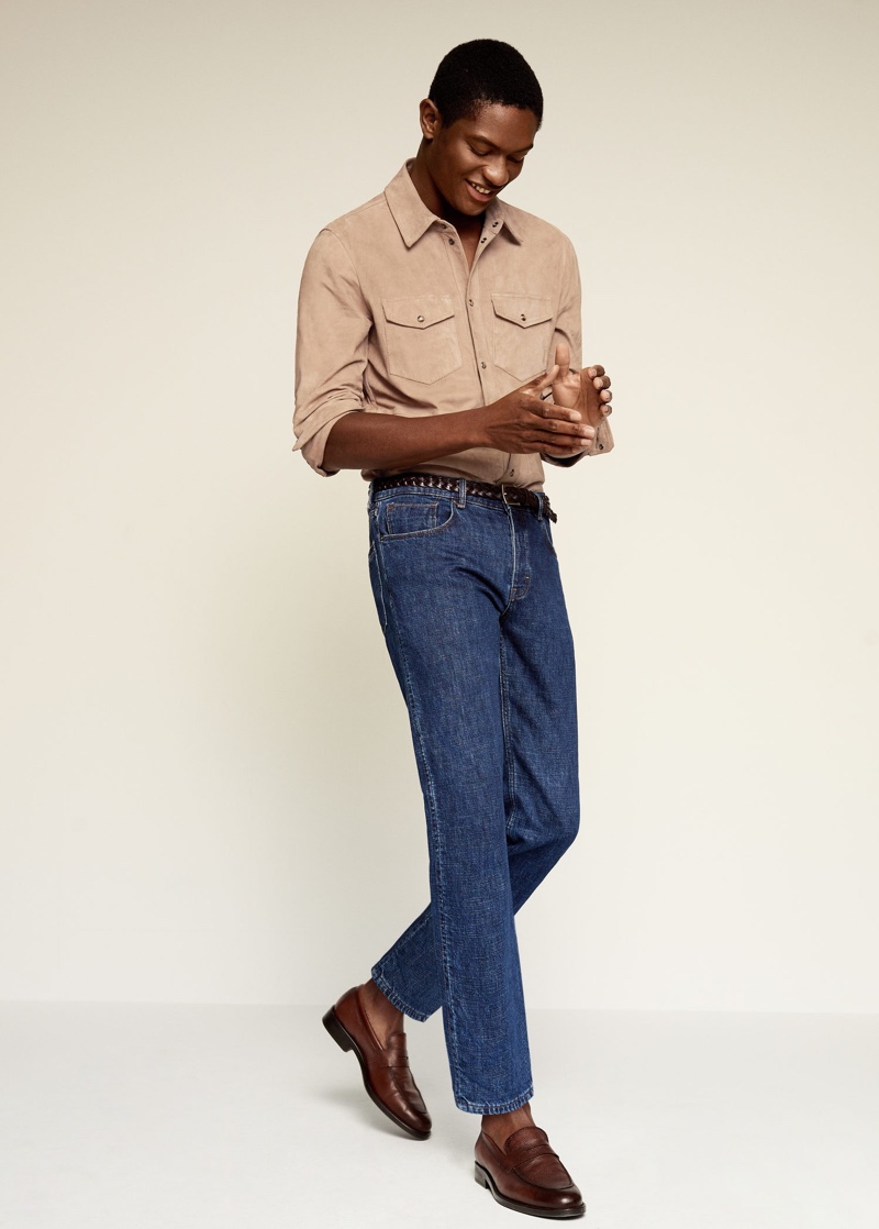 Model Hamid Onifade wears a Mango suede overshirt with dark wash denim jeans.