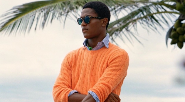 Hamid, Jegor & Jeenu Take to Bermuda in POLO Spring '20 Collection Hamid Onifade sports a bright orange cable-knit sweater with a striped oxford shirt and frayed white shorts by POLO Ralph Lauren.