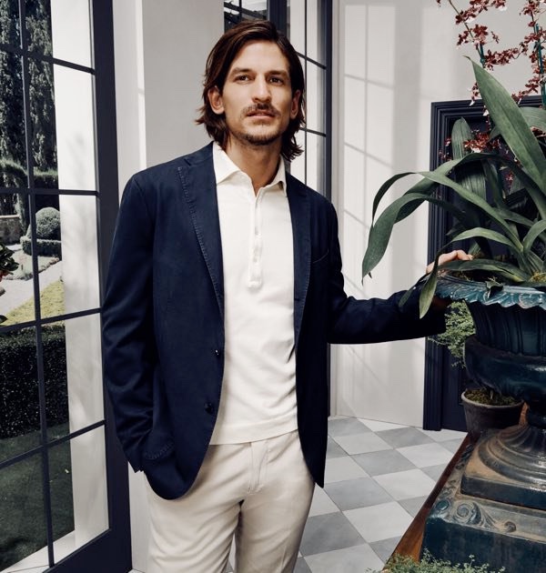 Jarrod Scott wears a Boglioli wool jacket, polo shirt, and khaki trousers. 