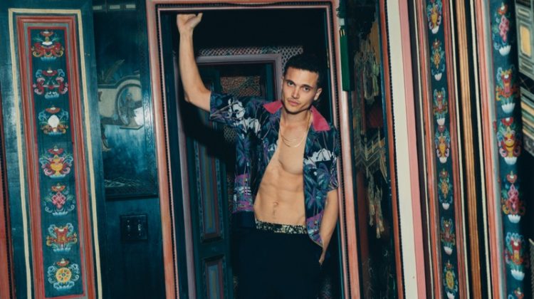 Posing in a charming room for Mr Porter, Karl Glusman dons a Sacai + Sun Surf camp-collar shirt with Dries Van Noten satin-trimmed trousers.