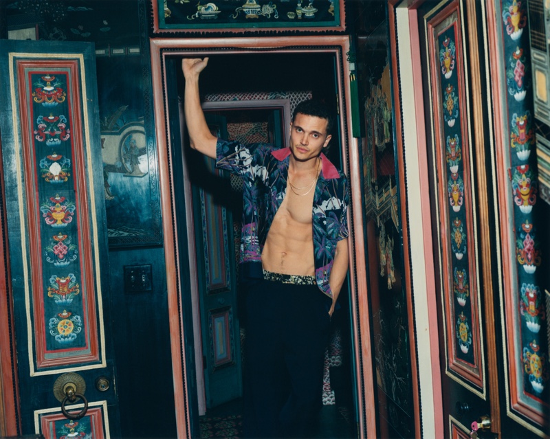Posing in a charming room for Mr Porter, Karl Glusman dons a Sacai + Sun Surf camp-collar shirt with Dries Van Noten satin-trimmed trousers. 