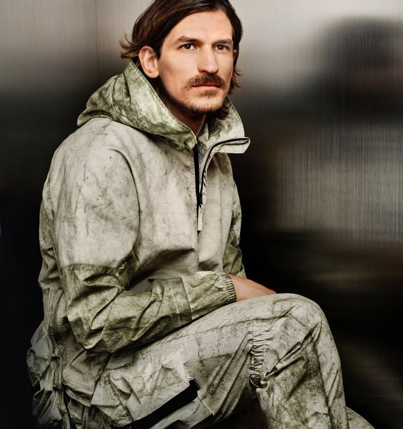 Jarrod Scott dons Stone Island's Membrana + Oxford 3l With Dust Color Finish anorak with cargo pants for Holt Renfrew.