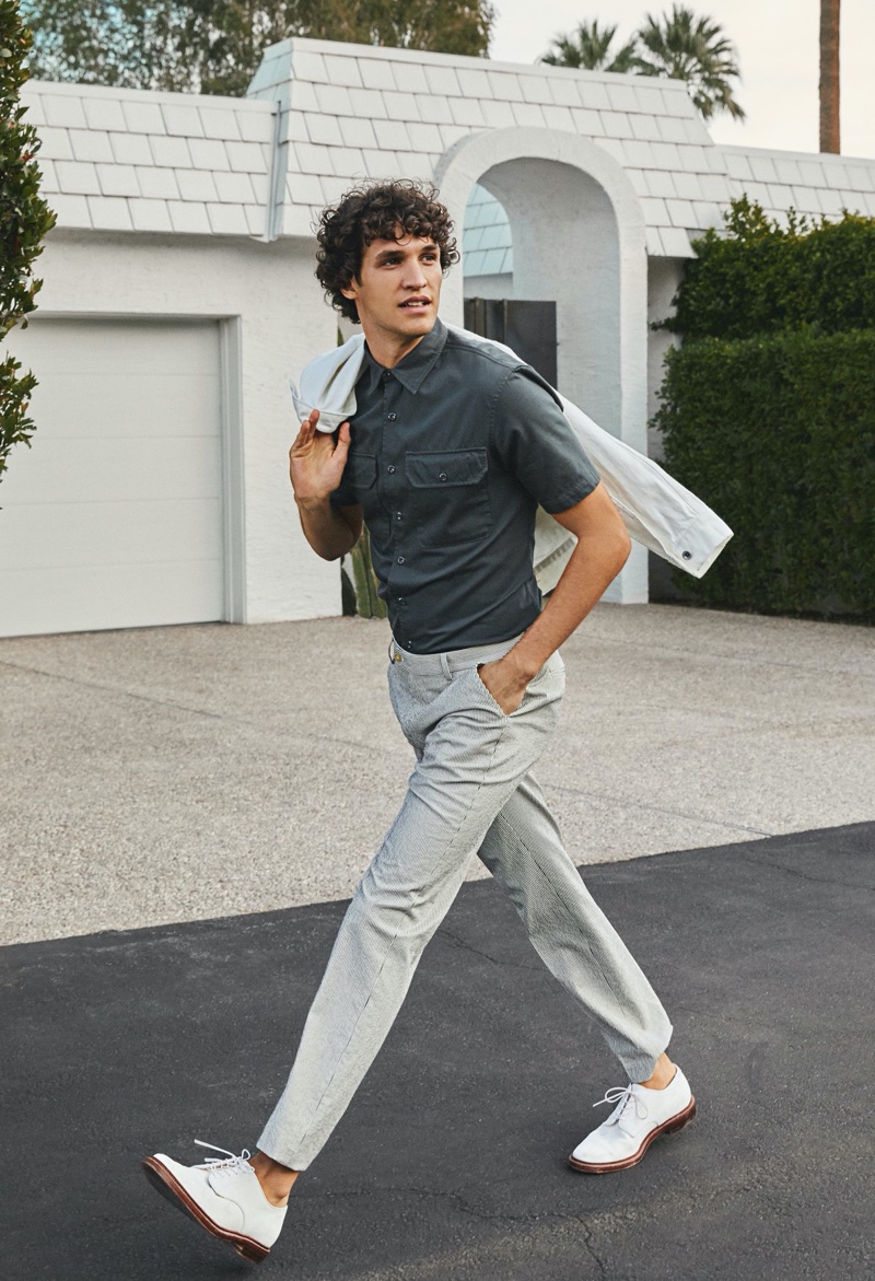 Embracing smart style, Francisco Henriques dons a Todd Snyder cord jacket, Italian two-pocket utility short-sleeve shirt, and seersucker tab dress trousers. The Portuguese model also sports Alden + Todd Snyder unlined suede white buck shoes.