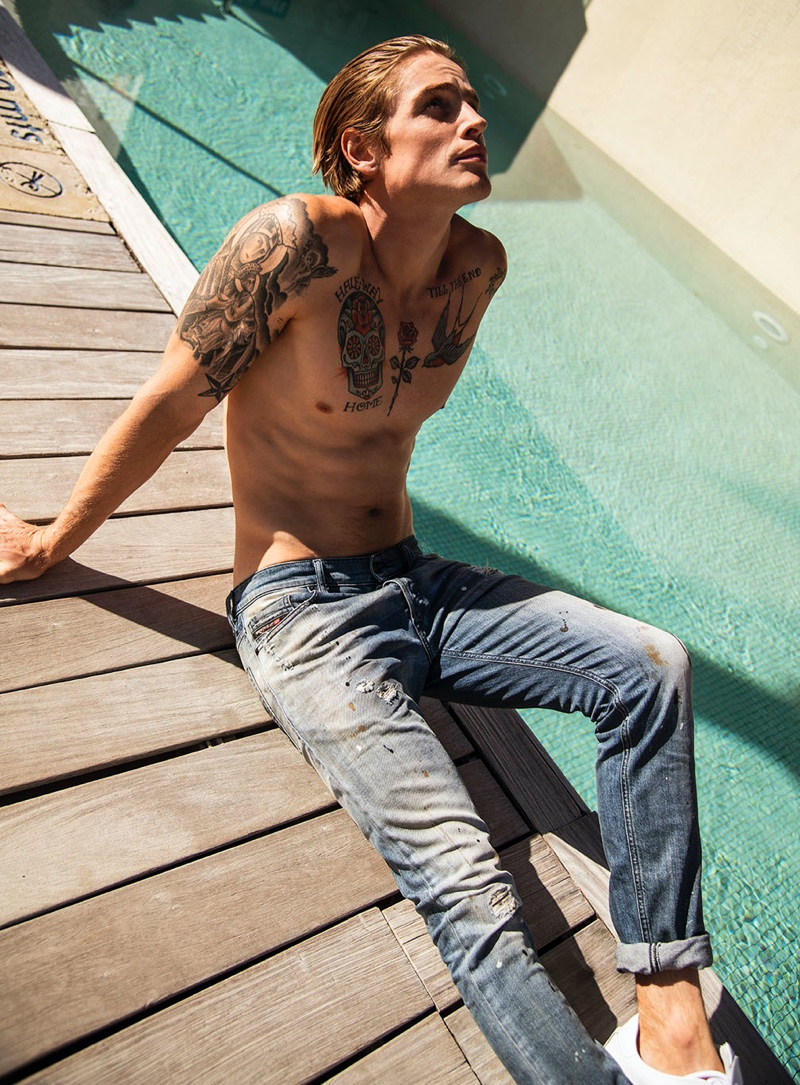 Fronting Wormland's spring-summer 2020 campaign, Patrick O’Donnell rocks a pair of distressed denim jeans by Diesel. The shirtless model also shows off his chest of tattoos.
