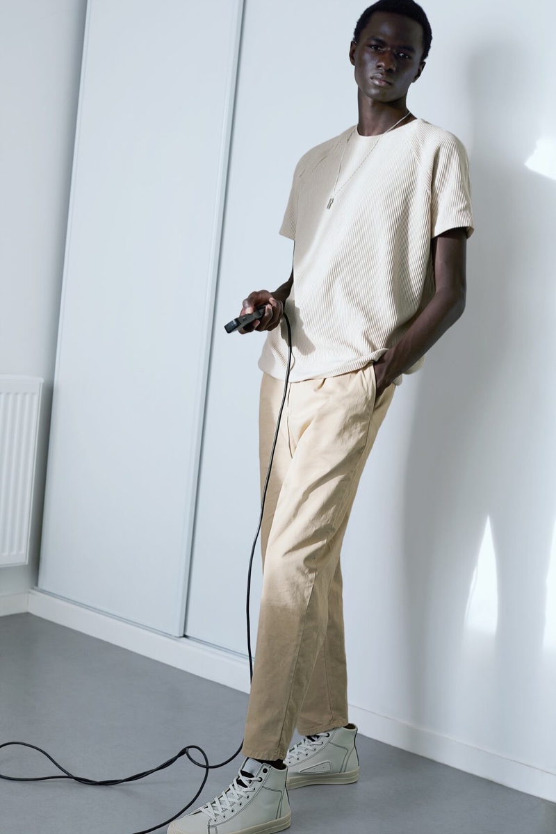 Posing for a photo, Malick Bodian dons a textured short-sleeve sweater with 1980s-inspired chinos by Zara.