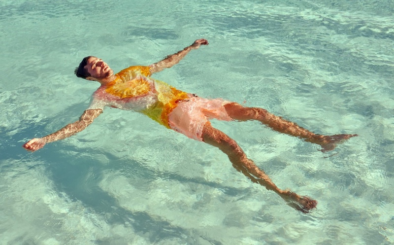 Relaxing in the pool, Arran Sly sports a tie dye t-shirt with garment dyed swim shorts from Scotch & Soda.