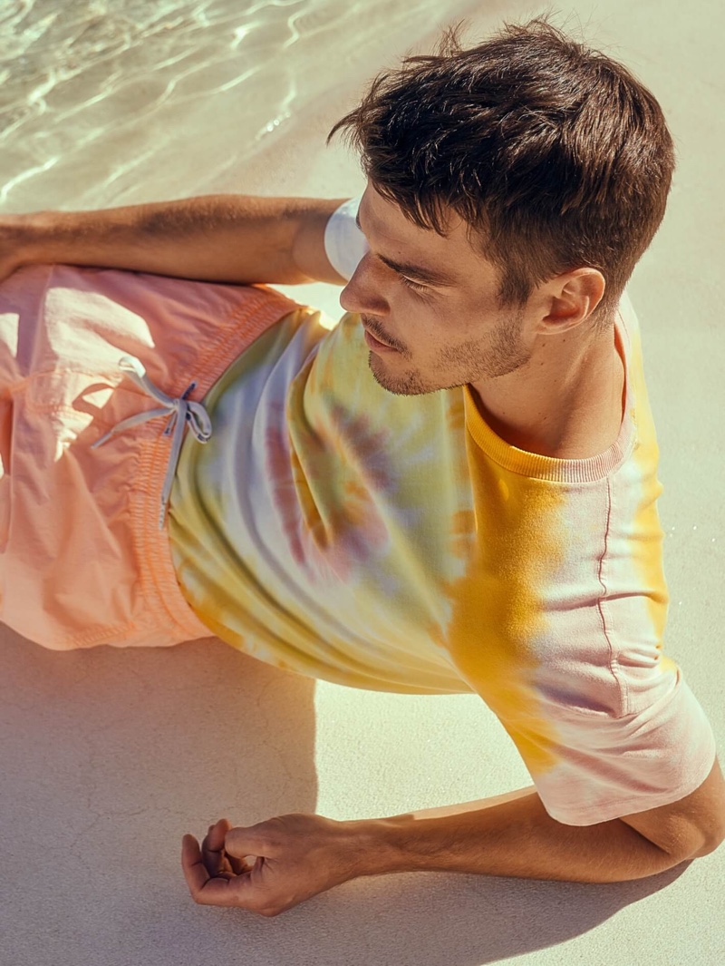 Embracing the essence of summer, Arran Sly models a Scotch & Soda tie dye t-shirt with garment dyed swim shorts.