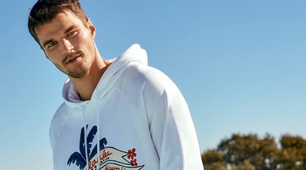 Scotch & Soda Takes Inspiration from Keoni for Summer Capsule Collection Arran Sly sports an artwork hoodie with mid-length swim shorts from Scotch & Soda's Keoni collection.