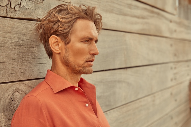 Delivering a side profile, Robertas Aukstuolis dons a coral Portofino linen shirt for Luca Faloni's high summer 2020 campaign.