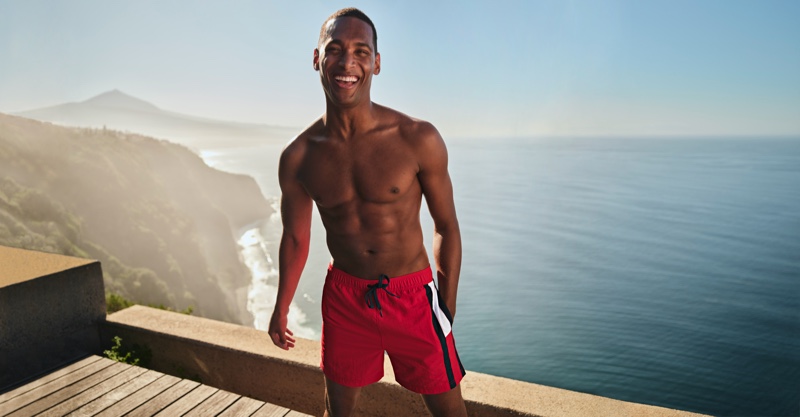 Model Patrick Nodanche wears color-blocked swim shorts by Tommy Hilfiger.