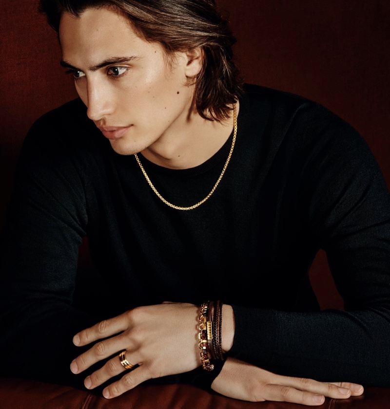 James Turlington dons a David Yurman box chain 18k gold necklace with a chevron triple-wrap leather bracelet with silver and southwest leather bracelet with 18k gold. He also models the label's Hex 18k gold spiritual bead bracelet, chain 18k gold bracelet, and deco 18k gold band ring.