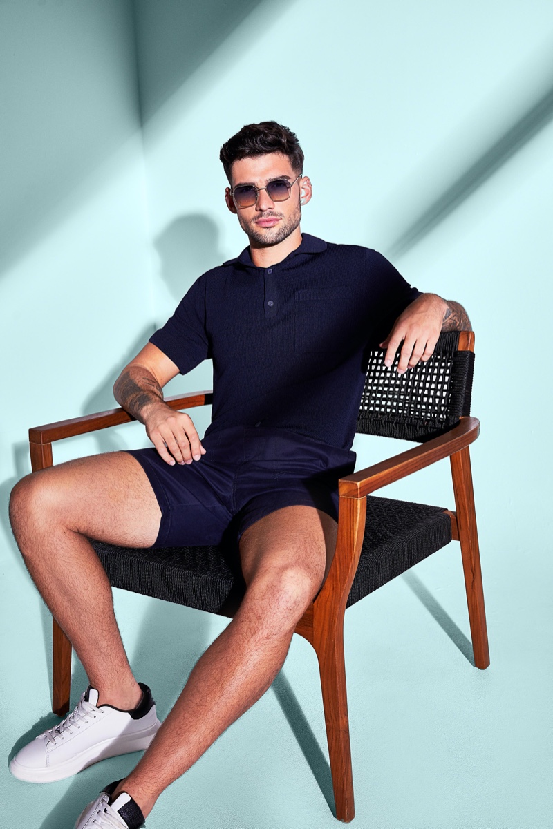 Showcasing monochromatic style, Brandan Stevens models a navy polo and tailored shorts from River Island.