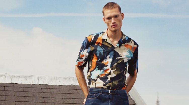 Taking to a rooftop in Amsterdam, William Los sports a graphic print short-sleeve shirt with classic blue denim jeans by Zara.