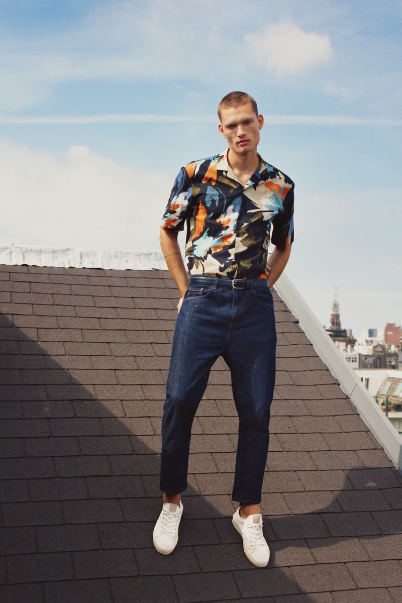 Taking to a rooftop in Amsterdam, William Los sports a graphic print short-sleeve shirt with classic blue denim jeans by Zara.