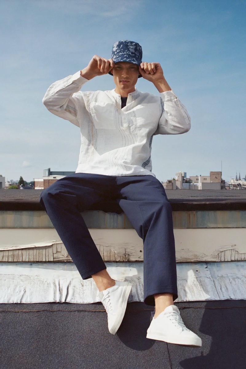 Enjoying a sunny day in Amsterdam, William Los wears a band-collar popover shirt from Zara with relaxed pants and a camouflage print bucket hat.