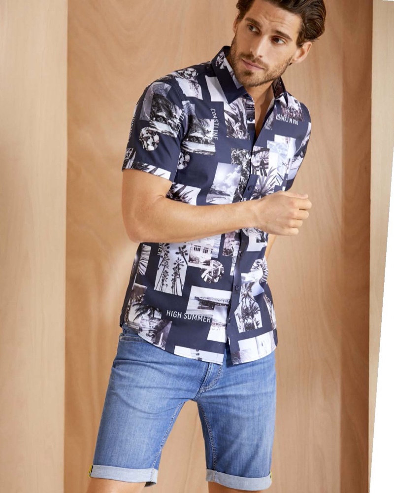 Simone Bredariol dons a "High Summer" short-sleeve shirt with denim shorts from BRAX's summer 2020 collection.