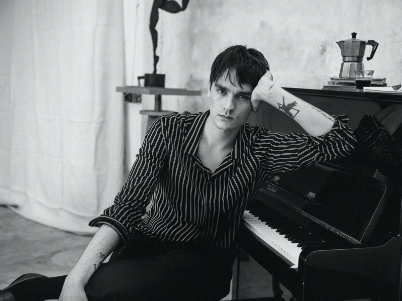 Posing against a piano, Alain-Fabien Delon sports a striped shirt with trousers from Mango Man. 