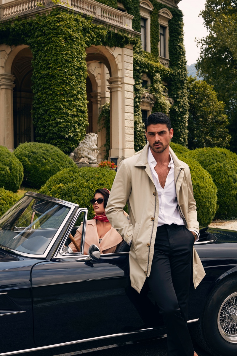 Michele Morrone dons a smart trench, white shirt, and trousers for GUESS' fall-winter 2020 campaign.