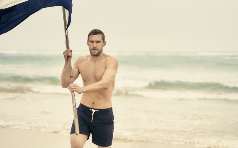 Will Chalker sports Orlebar Brown's Standard navy mid-length swim shorts.