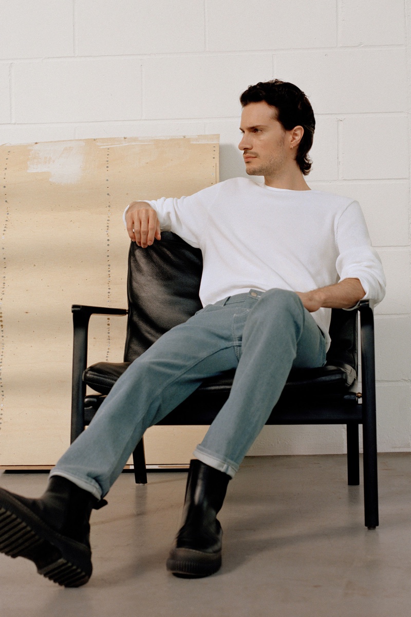 Relaxing, Tristan Pigott sports a COS ribbed pullover with recycled cotton slim-leg jeans.