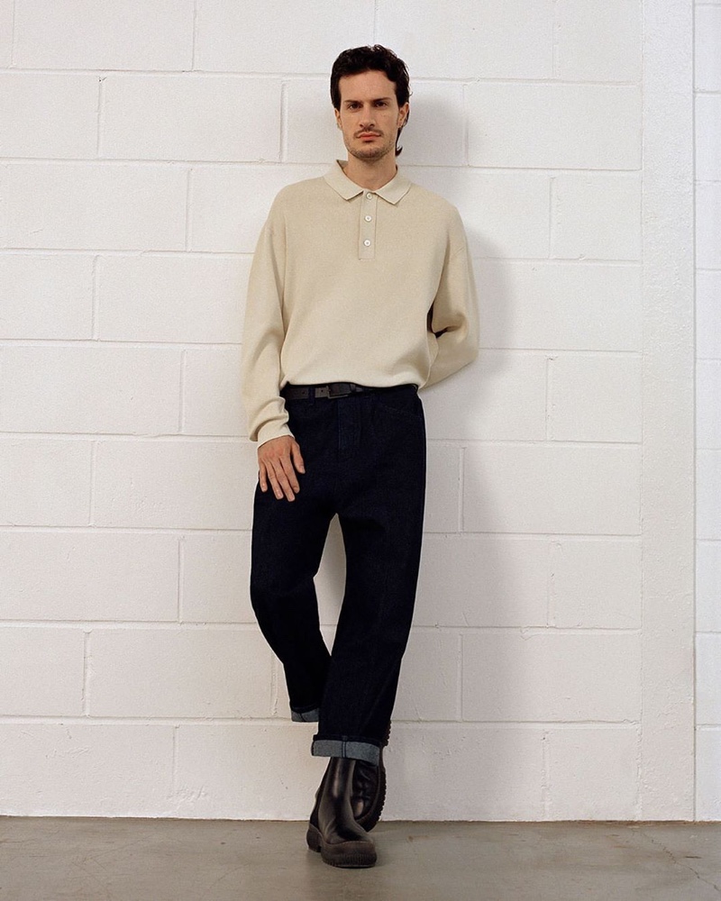 Front and center, artist Tristan Pigott wears a long-sleeve knit polo with sustainable denim jeans and chunky leather boots from COS.