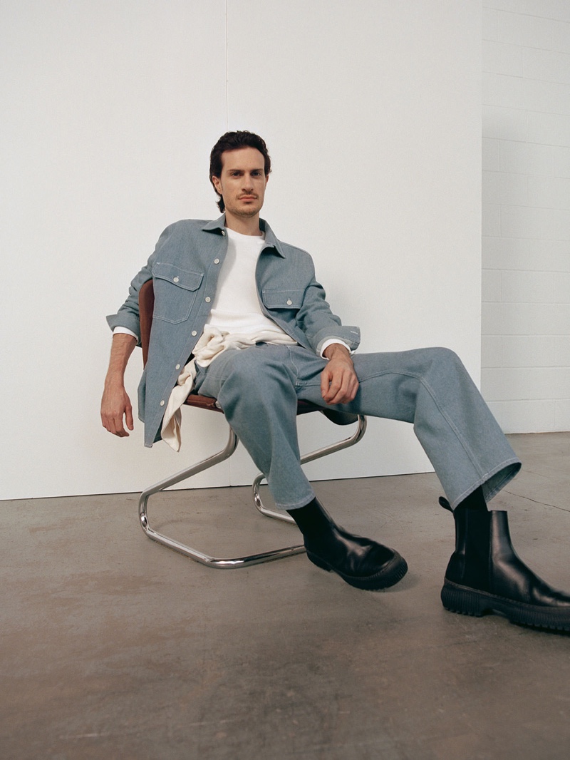 Figurative artist Tristan Pigott connects with COS for fall. He poses in the brand's organic cotton utility-style denim overshirt with a pair of recycled cotton denim cargo trousers.
