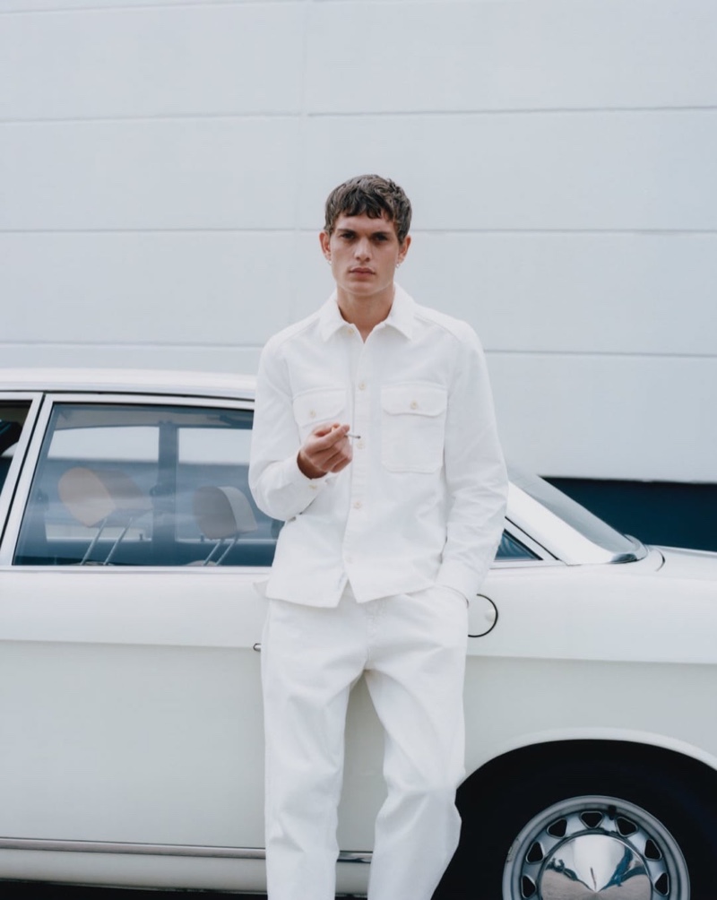 Clad in white, Julien Pernot wears menswear from fashion brand Closed.