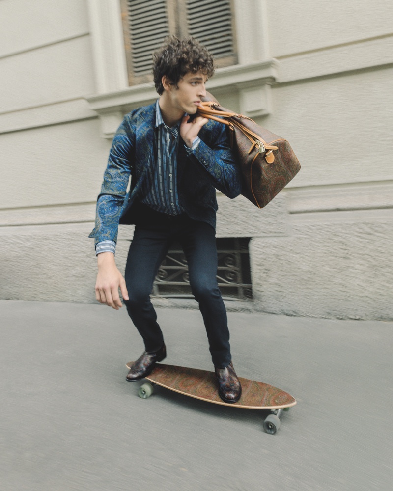 Skateboarding on an Etro longboard, Alberto Perazzolo models a paisley print 24 Hour jacket.