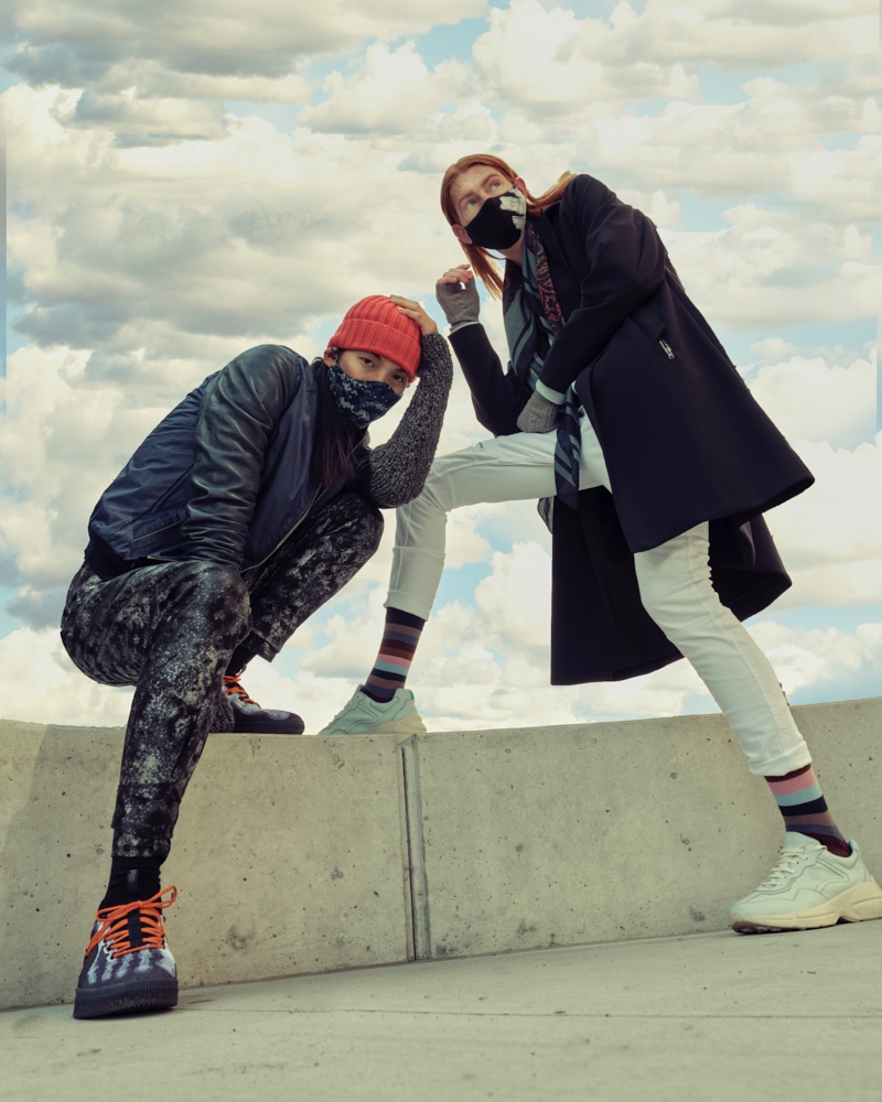 Left: Sooleen wears bomber Hip and Bone, beanie Leone Napoli, sneakers Puma, printed mask  Mayer Man Custom, tank and pants House of Dwir. Right: Jayden wears hand warmers Aldo, socks Hudson's Bay, sneakers Hip and Bone, mask, Mayer Man Custom, pants and scarf H&M, sweater and trench Christopher Bates.