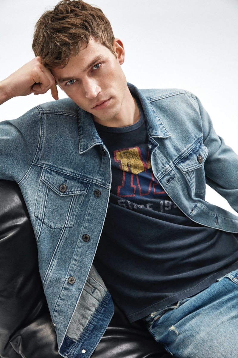 Model Jonas Fabienke sports a denim jacket with a graphic tee and jeans from Mavi's fall-winter 2020 collection.