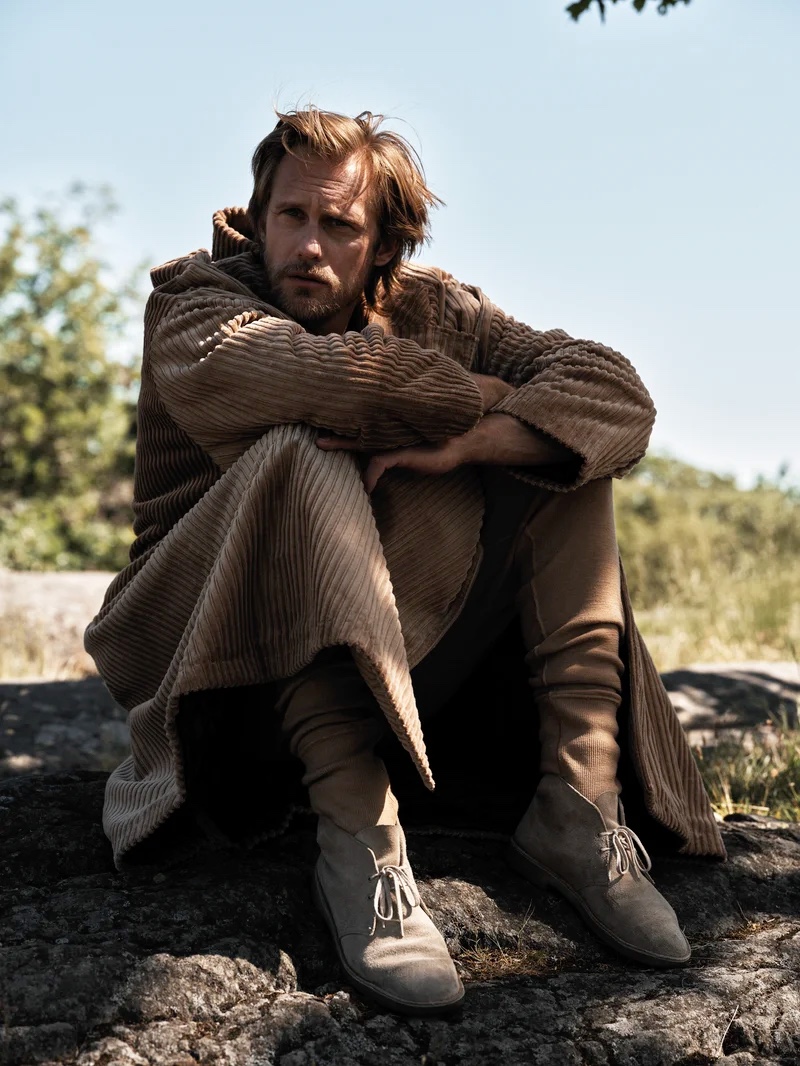 Actor Alexander Skarsgård sports a corduroy coat and joggers from Dolce & Gabbana for L'Uomo Vogue. He also wears Clarks desert boots.