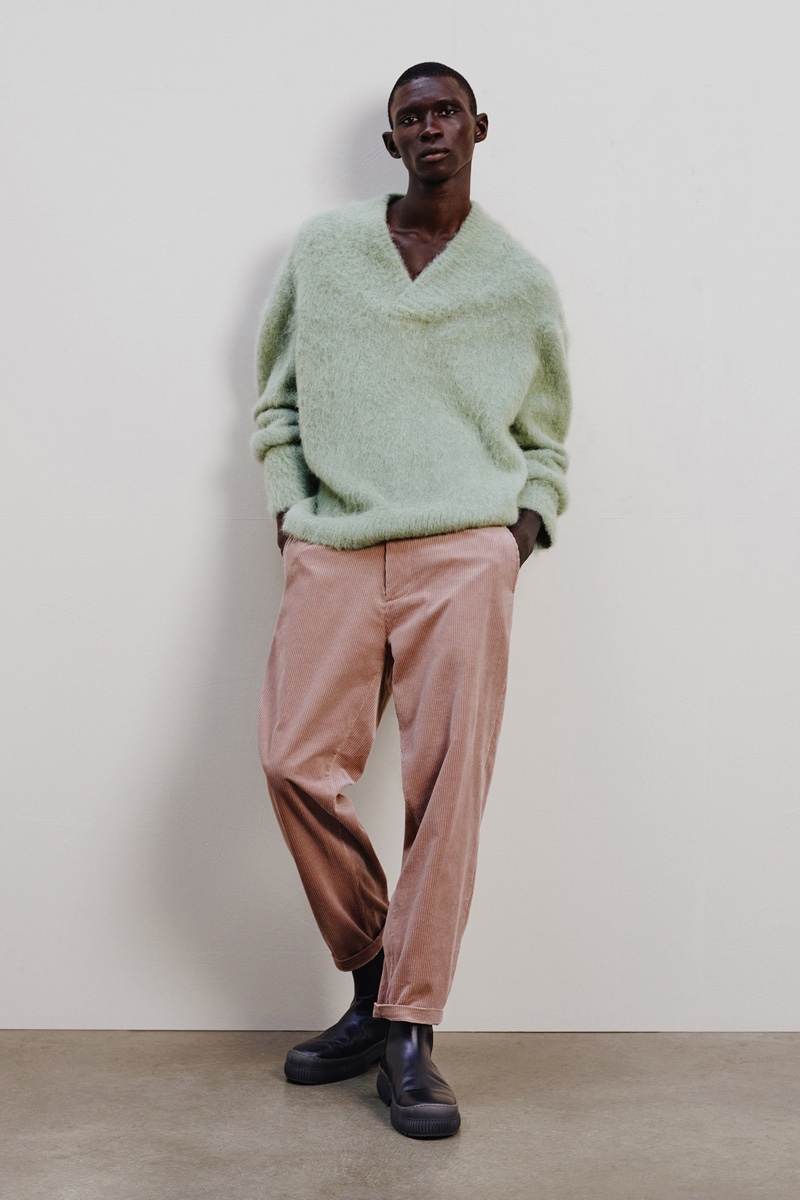 Mixing muted tones, Fernando Cabral stands out in a v-neck wool-mix sweater and corduroy trousers with chunky leather boots by COS.