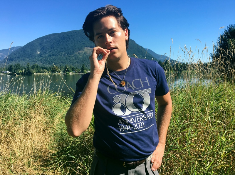 Cole Sprouse wears a t-shirt commemorating Coach's 80th anniversary.