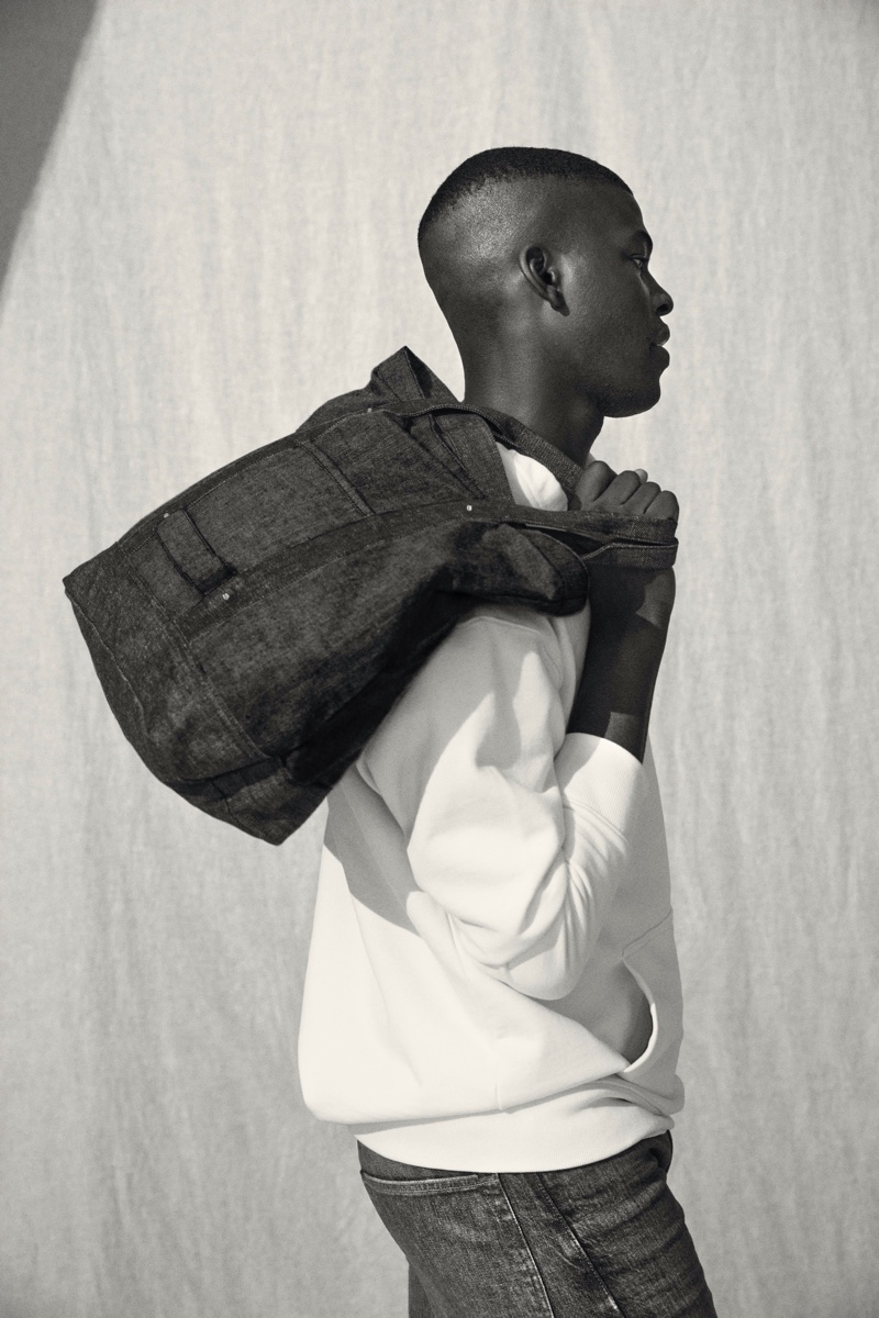 Connecting with H&M for fall, model Evandro Laurens takes hold of a denim tote from the brand's Jeans Redesign collection.