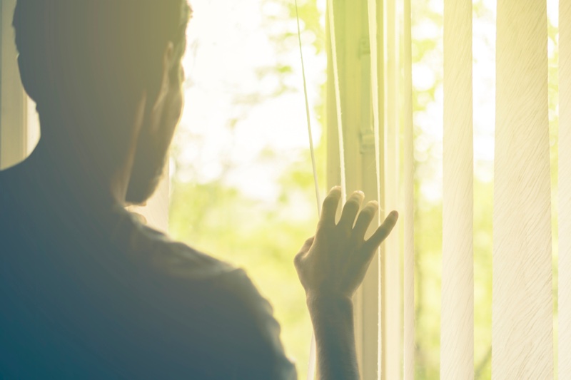 Man Looking Through Vertical Blinds Sun