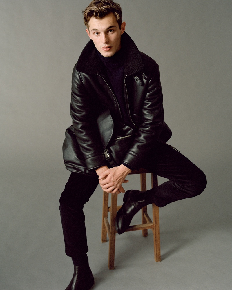 Kit Butler embraces contemporary style in a look from Mango's fall-winter 2020 Urban Essentials collection. The British model takes to the studio where he sits for a portrait. He dons a Mango leather jacket with slim-fit pants, a turtleneck, and leather boots.