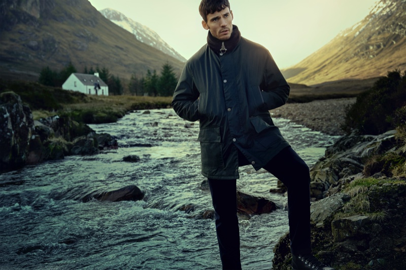 Barbour Gold Standard enlists Sam Claflin as the face of its fall-winter 2020 campaign. Posing for a photo, Claflin dons the brand's Supa Border wax jacket.